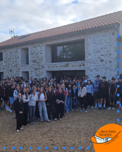Groupe de lycéens et lycéennes du Lycée Notre-Dame de la Tourtière posant devant un bâtiment en pierre et pierre de taille. Le logo de l'établissement, accompagné du slogan « Un tremplin pour tous », est visible en bas à droite de l'image.
